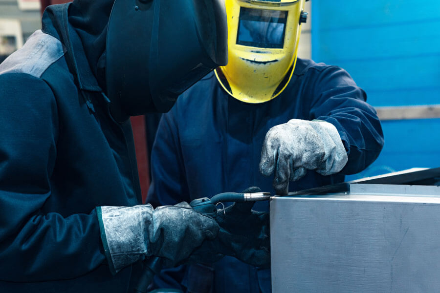 experienced worker instructing a new worker in welding