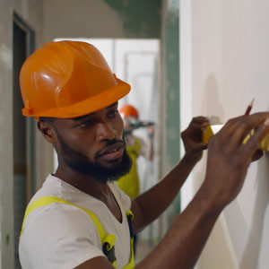 Man measuring a wall representing the construction industry.