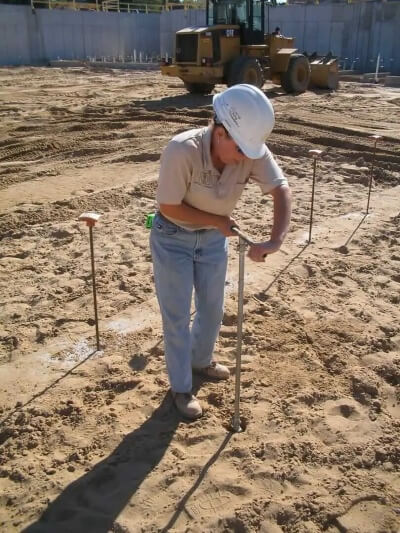 A geotechnical engineer collecting soil and rock samples during a field investigation