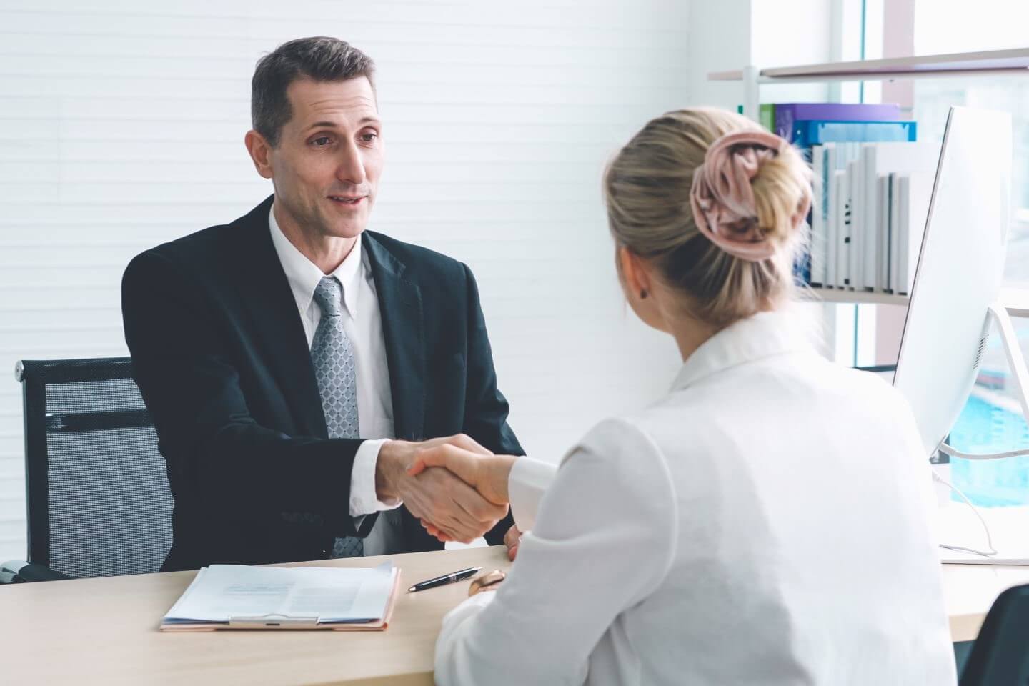 Woman interviewing for job, firm handshake with interviewer