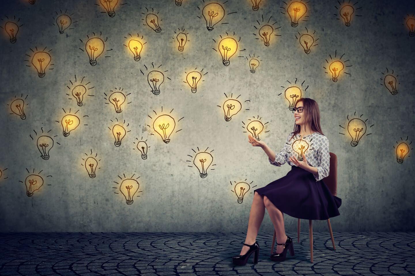 woman in chair holding light bulbs representing expanding skill sets