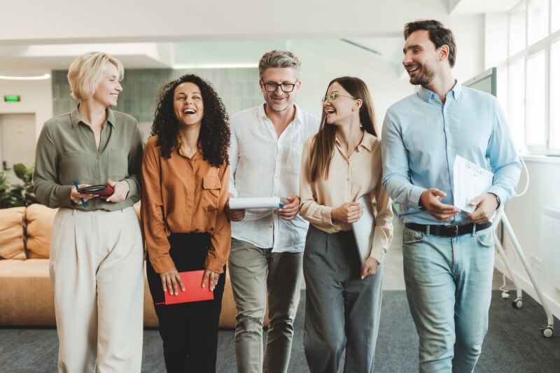 five diverse office professionals standing in group and smiling