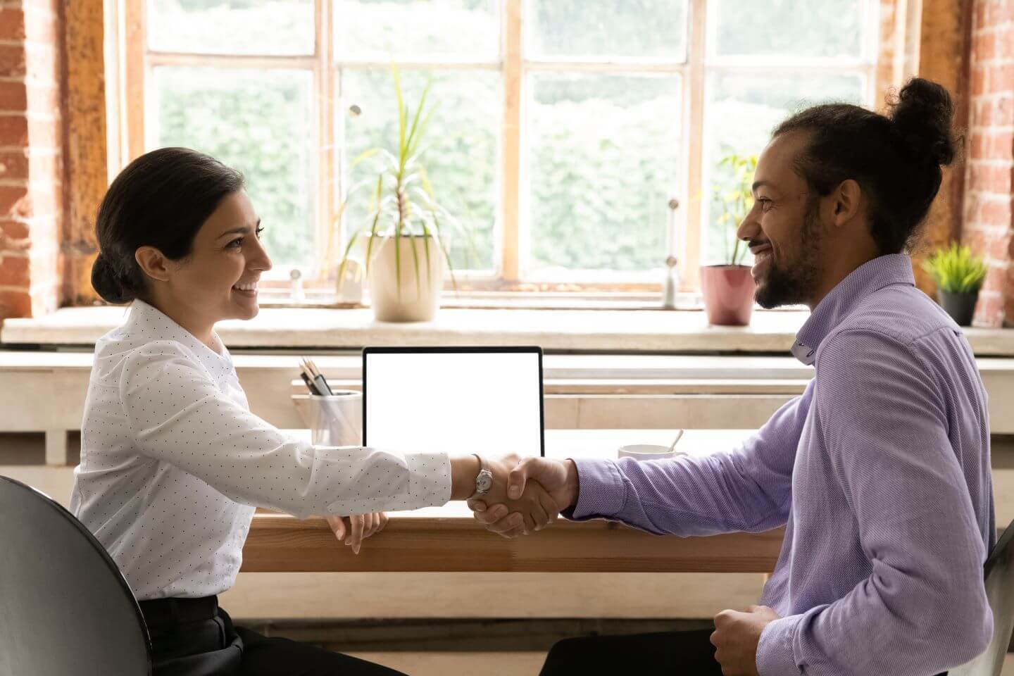 A woman and man shaking hands during a mock interview