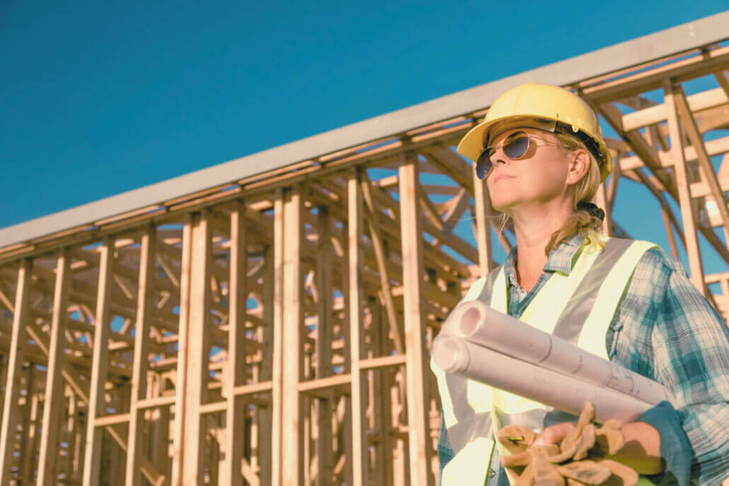 a female worker on a construction site holding floor plans and gloves