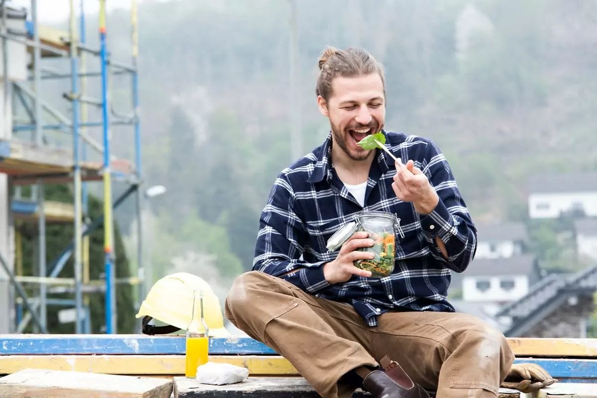 A construction worker enjoying a healthy salad and hearty sandwich on his lunch break at a construction site