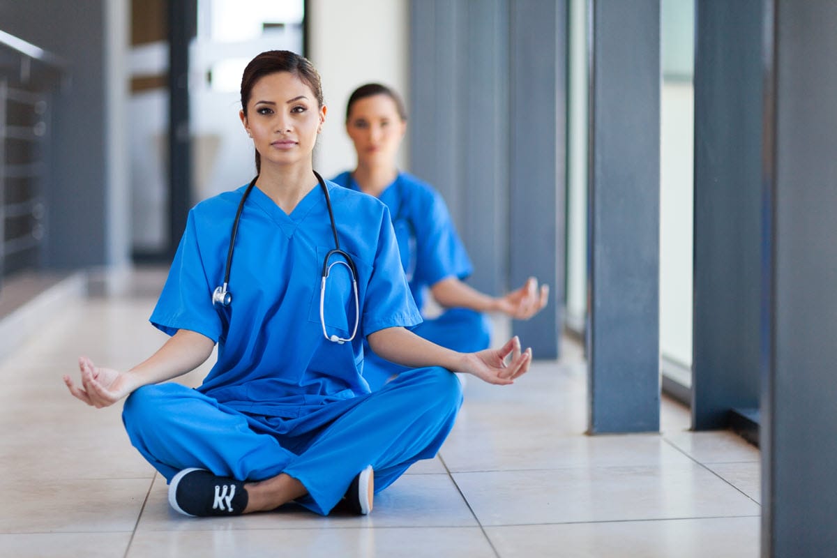 Healthcare workers meditating with colleagues to promote well being