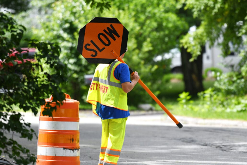 Construction worker holding slow sign demonstrating roadway safety