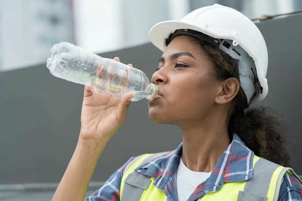 A female construction worker drinking from a water bottle