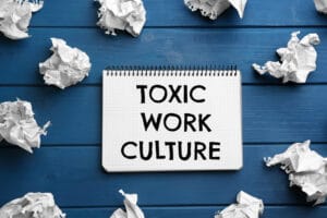 An notebook that says "Toxic Work Culture" implying the negative impacts of negative culture on employee wellbeing.