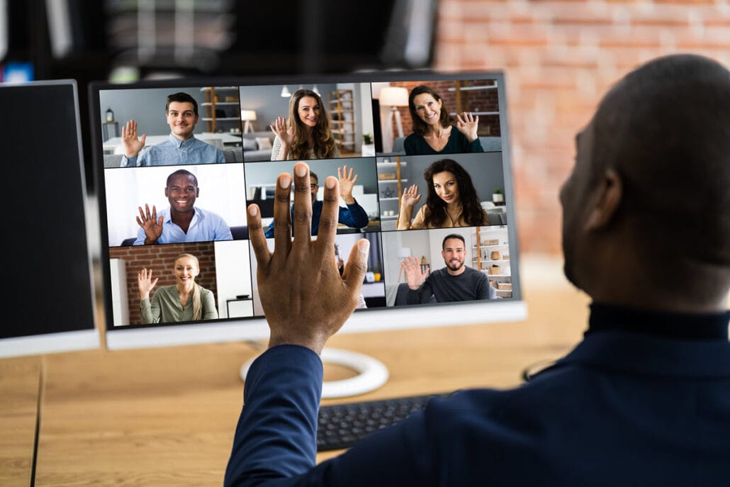 A man waving at others on a virtual meeting showing remote work as the new normal.