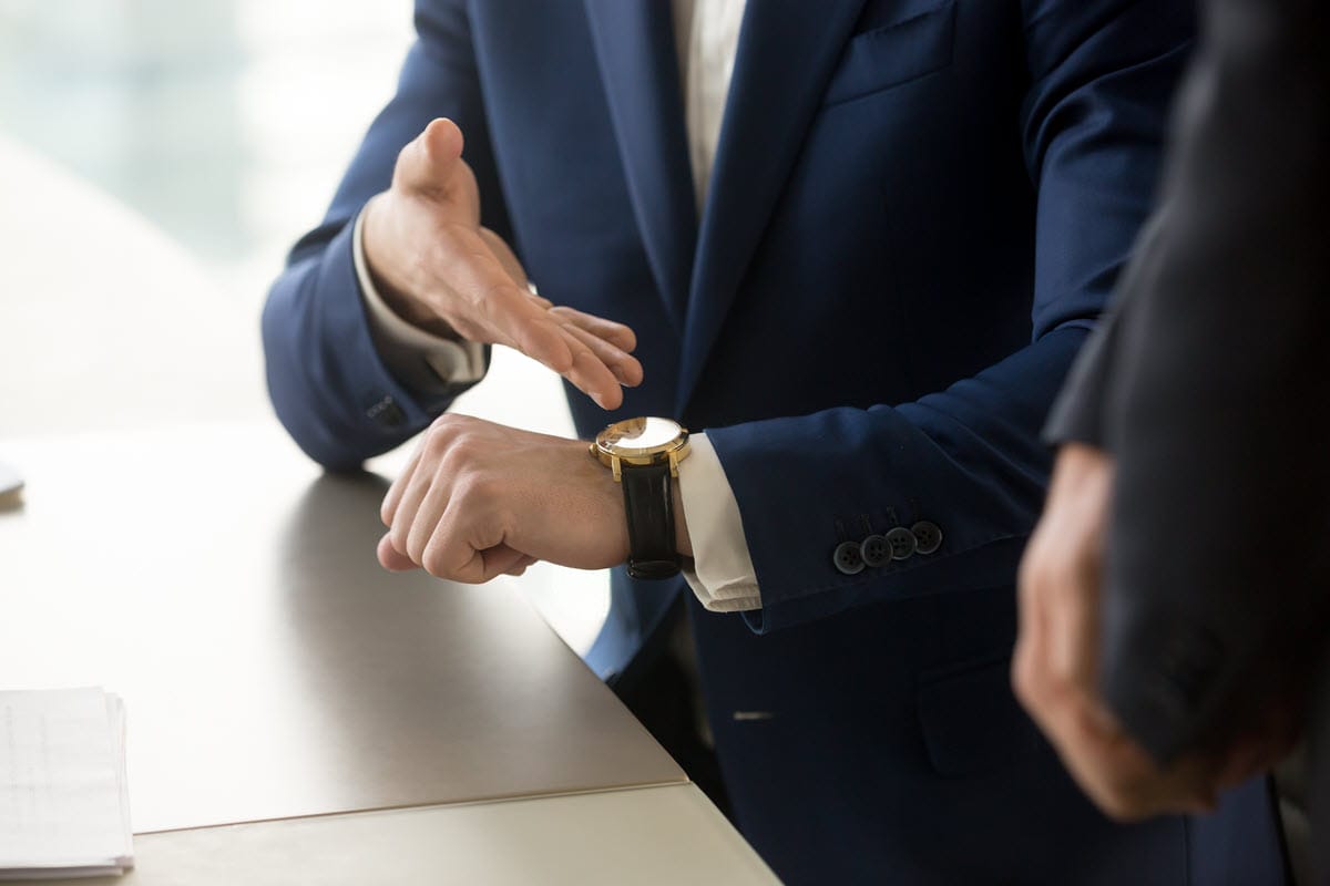 A manager gesturing to his watch to depict struggling with excessive absenteeism with employees