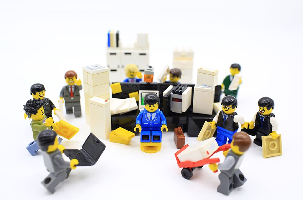 Lego workers surrounding man having a hard time with multiple requests