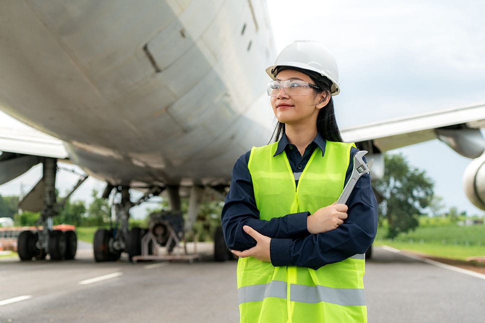 woman with aerospace engineering career standing proudly in front of an airplane