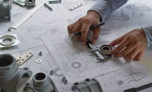 mechanical engineers hands creating blueprints using calipers and a pen